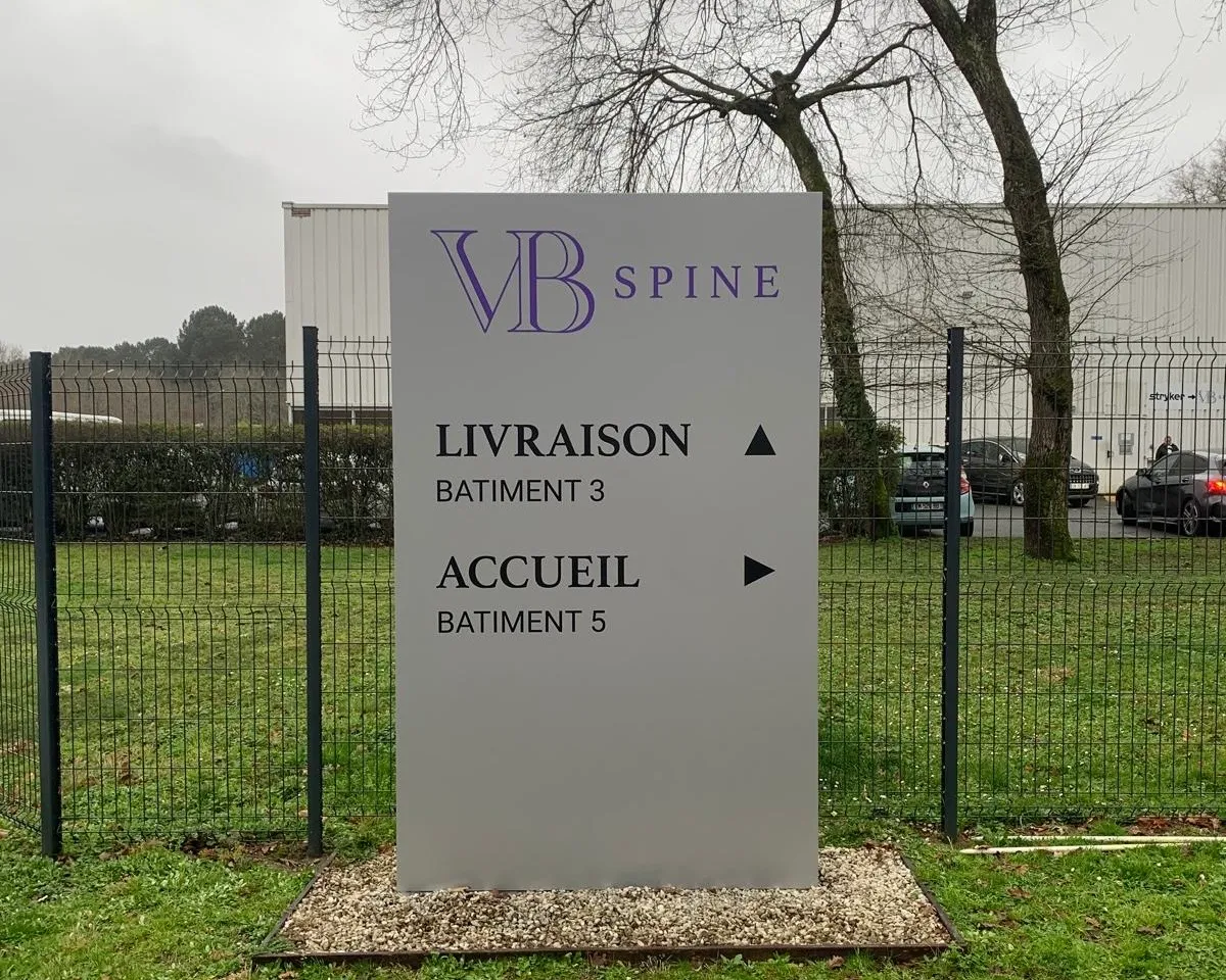 VB Spine, Cestas — totem directionnel différenciant les flux livraison et accueil entre bâtiments — réalisation PUBLI MENI