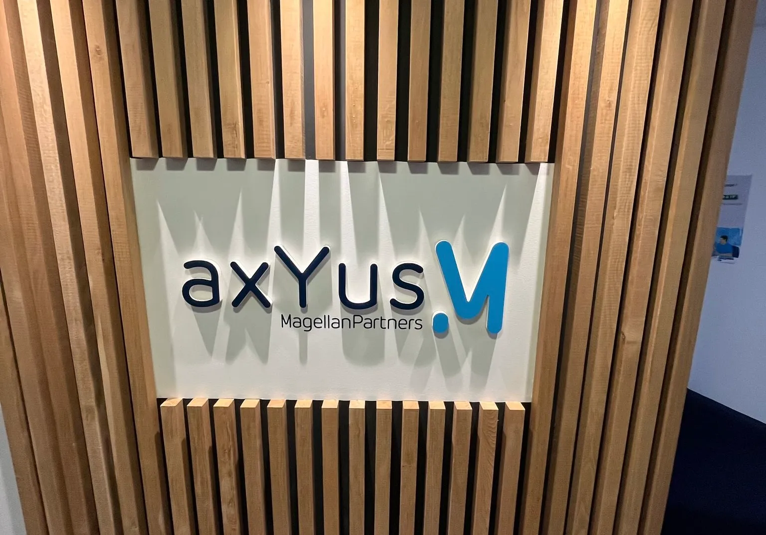 AXYUS, Mérignac — logo aXYus en relief sur habillage bois à l'accueil — réalisation PUBLI MENI